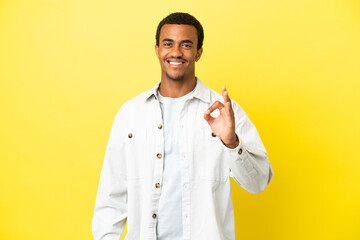 African American handsome man on isolated yellow background showing ok sign with fingers