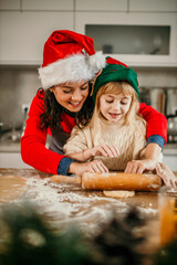 A mom and her little girl embrace the holiday spirit, joyfully making Christmas cookies together in their cozy kitchen