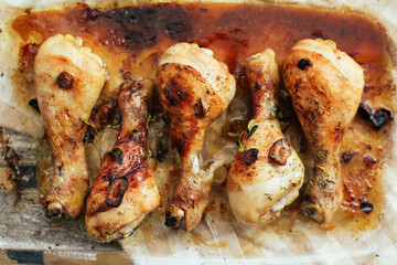 Roasted chicken legs with garlic, oil on a glass tray 