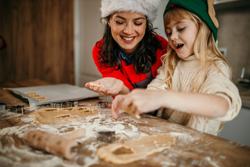 Mother and child daughter girl are cooking cookies and having fun in the kitchen. Homemade food and little helper. - obrazy, fototapety, plakaty