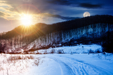 landscape with leafless forest on a snow covered hill beneath a sky with sun and moon. winter...