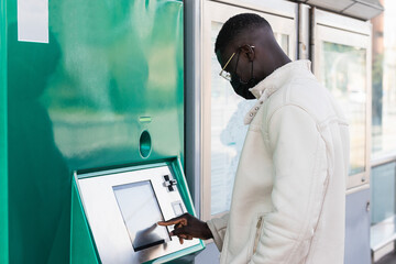 Black man using ticket machine on train or bus station