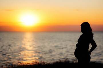 silhouette of a pregnant woman on the beach at sunset