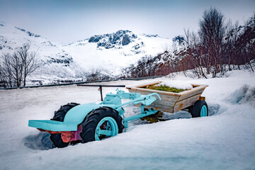 Mini tractor with wooden trailer on the shore of Vatterfjordpollen fjord. Gloomy winter scene of...