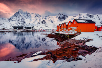 Norwegian red houses in Ballstad town on the shore of Norwegian sea. Dramatic sunseton Lofoten...