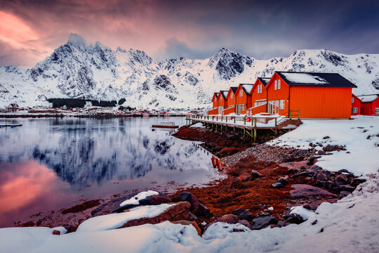 Norwegian red houses in Ballstad town on the shore of Norwegian sea. Dramatic sunseton Lofoten Islands archipelago, Norway, Europe. Life over polar circle. Traveling concept background..
