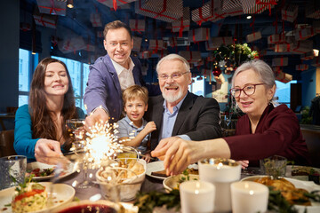 Cheerful family with sparkling Bengal lights enjoying Christmas party
