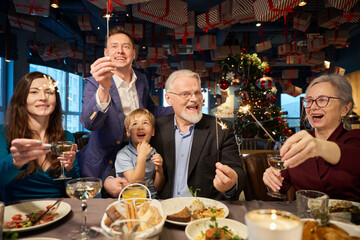 Overjoyed people with sparkling and glasses of champagne celebrating New Year