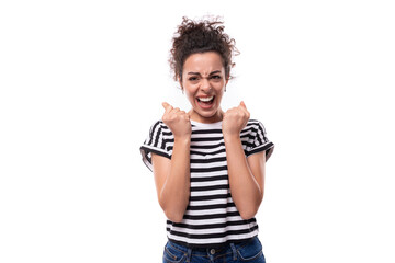 young happy curly brunette lady with black hair dressed in a striped t-shirt rejoices on a white background. people emotions concept