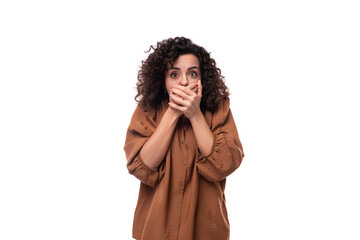 young curly leader woman in a brown blouse covered her mouth with her hand in surprise