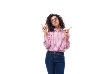 young european curly brunette lady in a pink blouse gesturing against the background with copy space