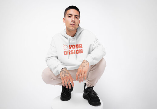 Mockup of man wearing customizable hoodie, crouching