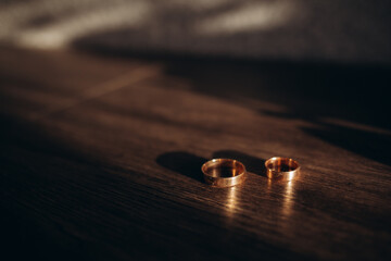 Wedding rings on a wooden box with shadows of leaves. Wedding ring