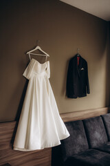 Bride and groom dresses hangs on the wall in the hotel