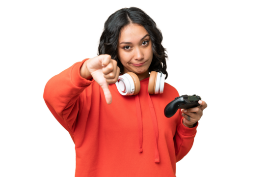 Young Argentinian woman playing with a video game controller over isolated background showing thumb down with negative expression