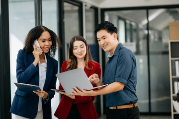 Happy businesspeople while collaborating on a new project in an office. Group of diverse businesspeople using a laptop and tablet .