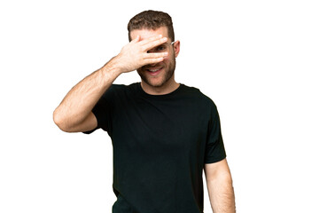Young handsome blonde man over isolated chroma key background covering eyes by hands and smiling