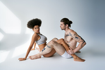appealing young multicultural couple in sexy comfy underwear sitting on floor, togetherness