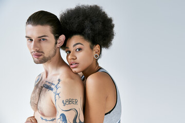 good looking african american woman hugging her tattooed boyfriend from behind, sexy couple