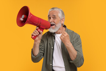 Happy senior sports fan using megaphone on yellow background