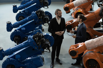 Group of businessmen discussing in the autonomous robotics warehouse storage. Industrial...