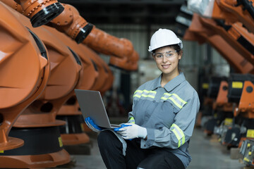 Female engineer working and checking, repair, maintenance autonomous robotics arm, using laptop...