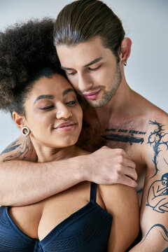 appealing young multicultural boyfriend and girlfriend in underwear hugging warmly, togetherness