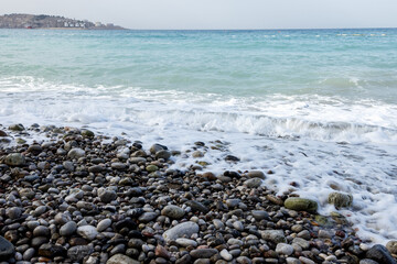 The blue Adriatic Sea rolls over the rocks. The port is far away
