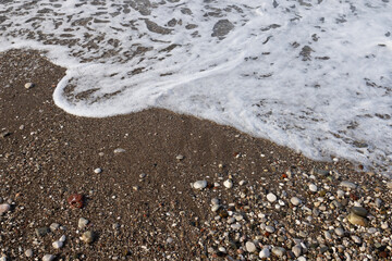 Small pebbles, sand. The receding sea wave