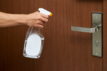 Man disinfecting the Door knob by spraying a white sanitizer from a bottle, Prevent covid19, corona...