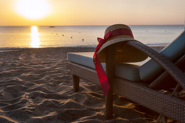 A woman's hat is lying on a chaise longue. Dawn on the beach. The coast of the Indian Ocean. The...