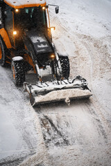 Tractor shoveling snow on the street.