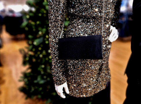 the woman mannequin in the shopping mall is wearing a black purse and dress with sparkles and sequins. golden highlights party dressed
