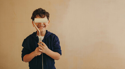 Happy child playfully holding a painting brush over his eyes during a home renovation activity