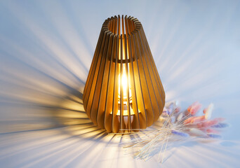 Wooden eco-friendly interior table lamp - night light shines next to multi-colored dried flowers on a light background. Photo. Copy space.