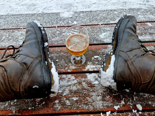 man takes a glass of beer and toasts his health in the middle of winter covered with snow. glass on...