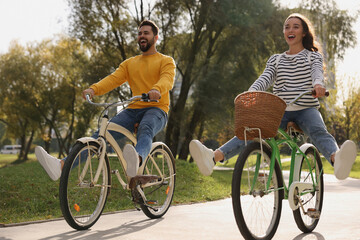 Obraz premium Beautiful young couple riding bicycles in park