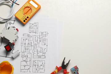 Flat lay composition with wiring diagrams and digital multimeter on white table, space for text