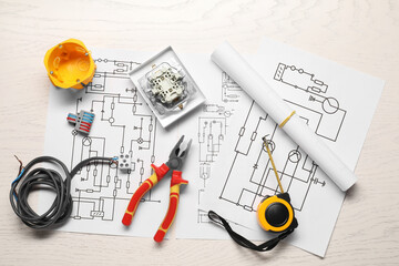 Wiring diagrams, pliers and different electrician's equipment on white wooden table, flat lay