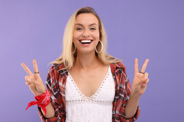 Portrait of happy hippie woman showing peace signs on purple background