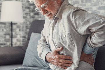 Upset senior elder man feel sudden back pain muscles ache tension injury sitting at home, sad old...
