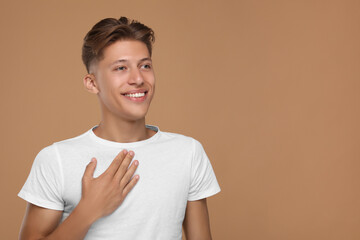 Thank you gesture. Handsome grateful man with hand on chest against brown background, space for text