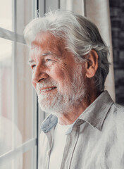 Happy thoughtful older 70s man looking out of window away with hope, thinking of good health,...