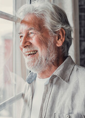 Happy thoughtful older 70s man looking out of window away with hope, thinking of good health,...