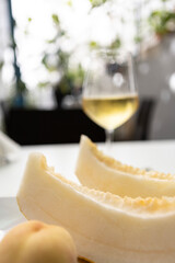 Yellow melon slices, a peach and a glass of sparkling wine on a sunny summer day