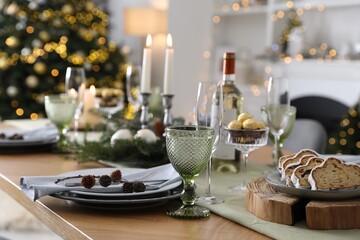 Christmas table setting with festive decor and dishware in room