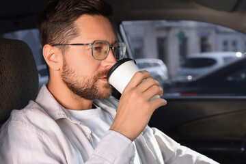 To-go drink. Handsome man drinking coffee in car