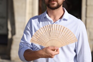 Man with hand fan outdoors, closeup view