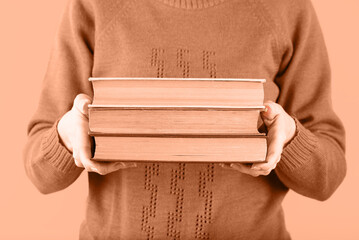 Stack of old books in the hands of a girl on a peach, education, learning, study, compassion,...