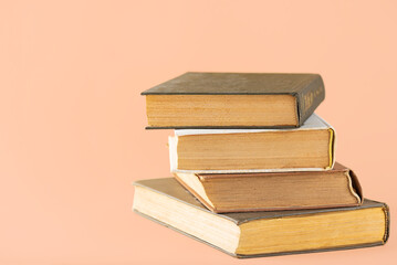 Stack of books on peach background, education, learning, study, culture.